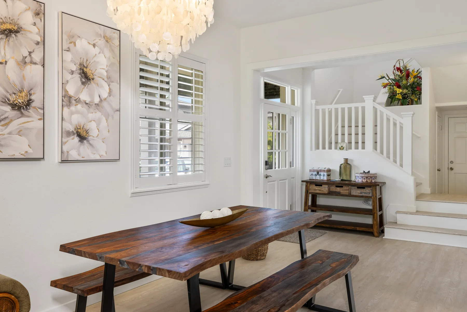 Comedor con mesa y bancos de madera junto a una escalera.