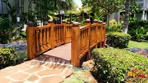 Un puente de madera cruza un sendero ajardinado.
