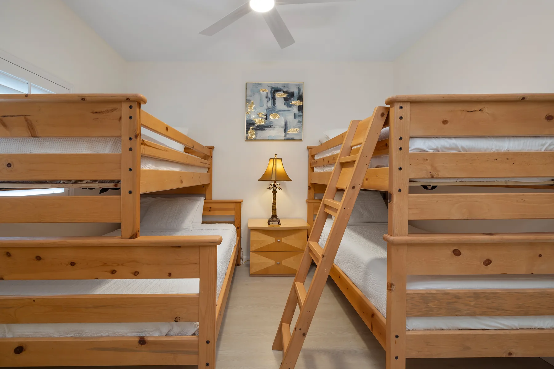 Un dormitorio con literas de madera y una mesita entre ellas.