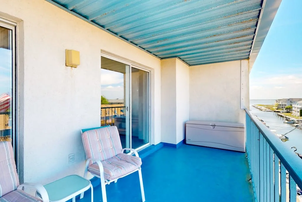 A covered balcony with seating and a storage chest overlooks the water.