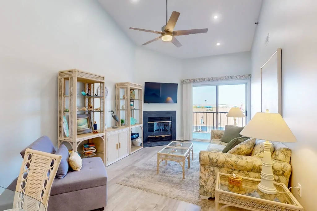 A bright living room with seating, a coffee table, and sliding glass doors.