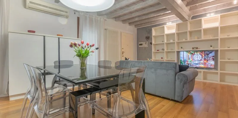 A living and dining area with a glass table, seating, and built-in shelving.