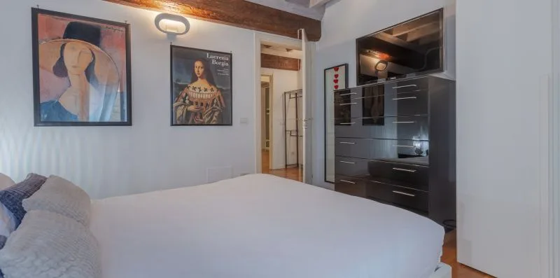 Un dormitorio con una cama, cuadros enmarcados y armarios oscuros.