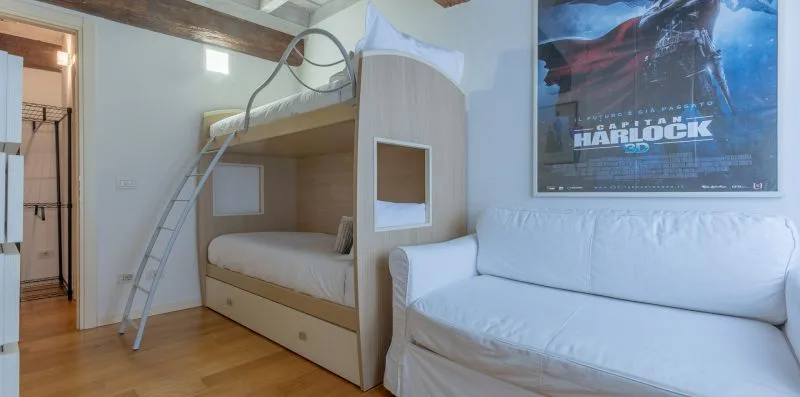 Un dormitorio con literas y un sofá blanco.