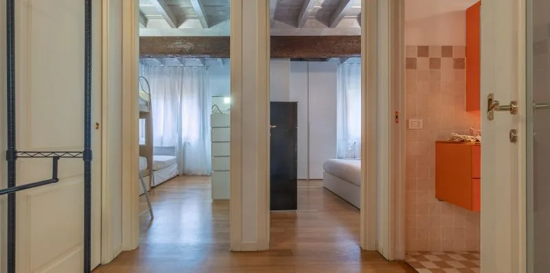 Un pasillo interior da a un dormitorio y un baño con azulejos.