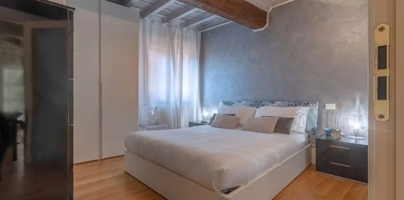 Un dormitorio con una cama, una mesita de noche y una ventana con cortinas.