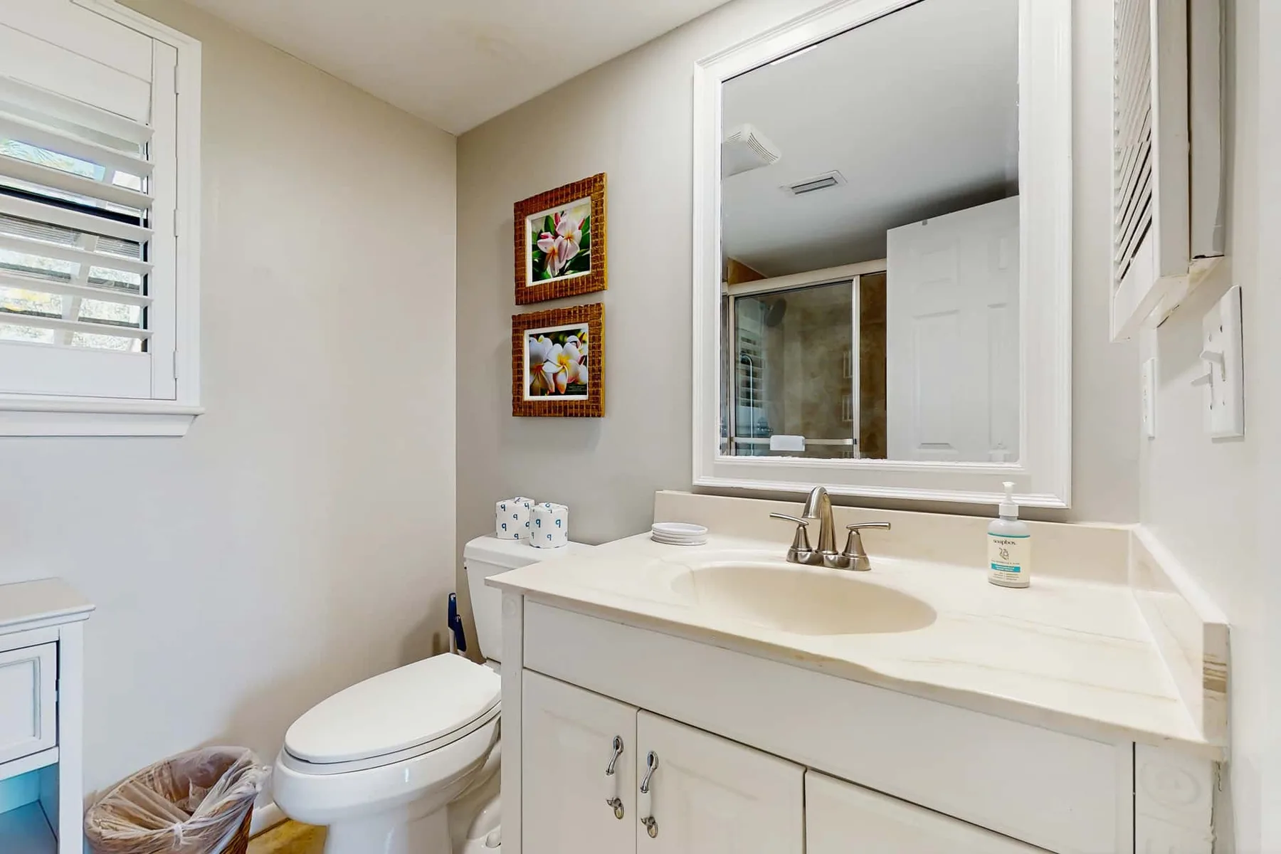 A bathroom with a white vanity, sink, and mirror.