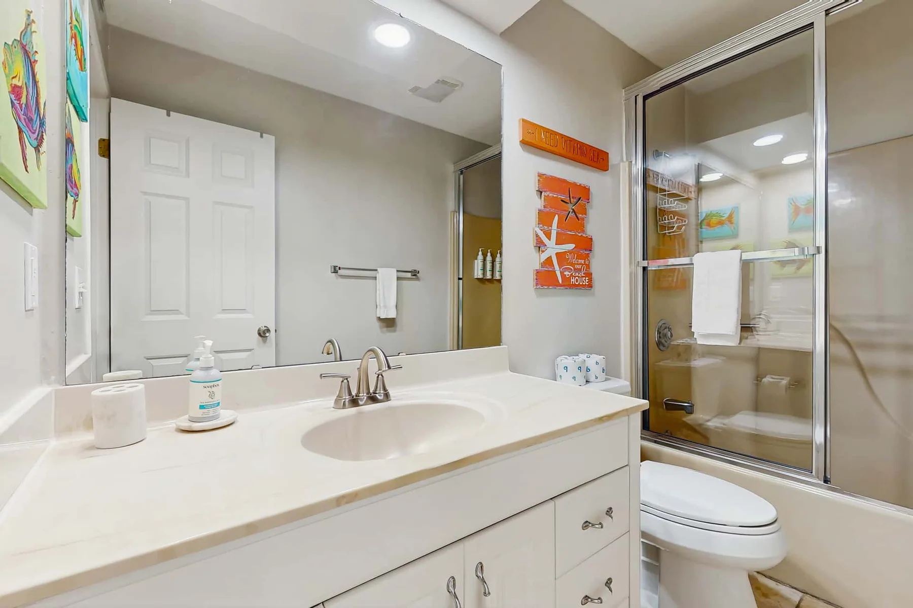 A bathroom with a wide vanity, sink, and glass-enclosed shower.