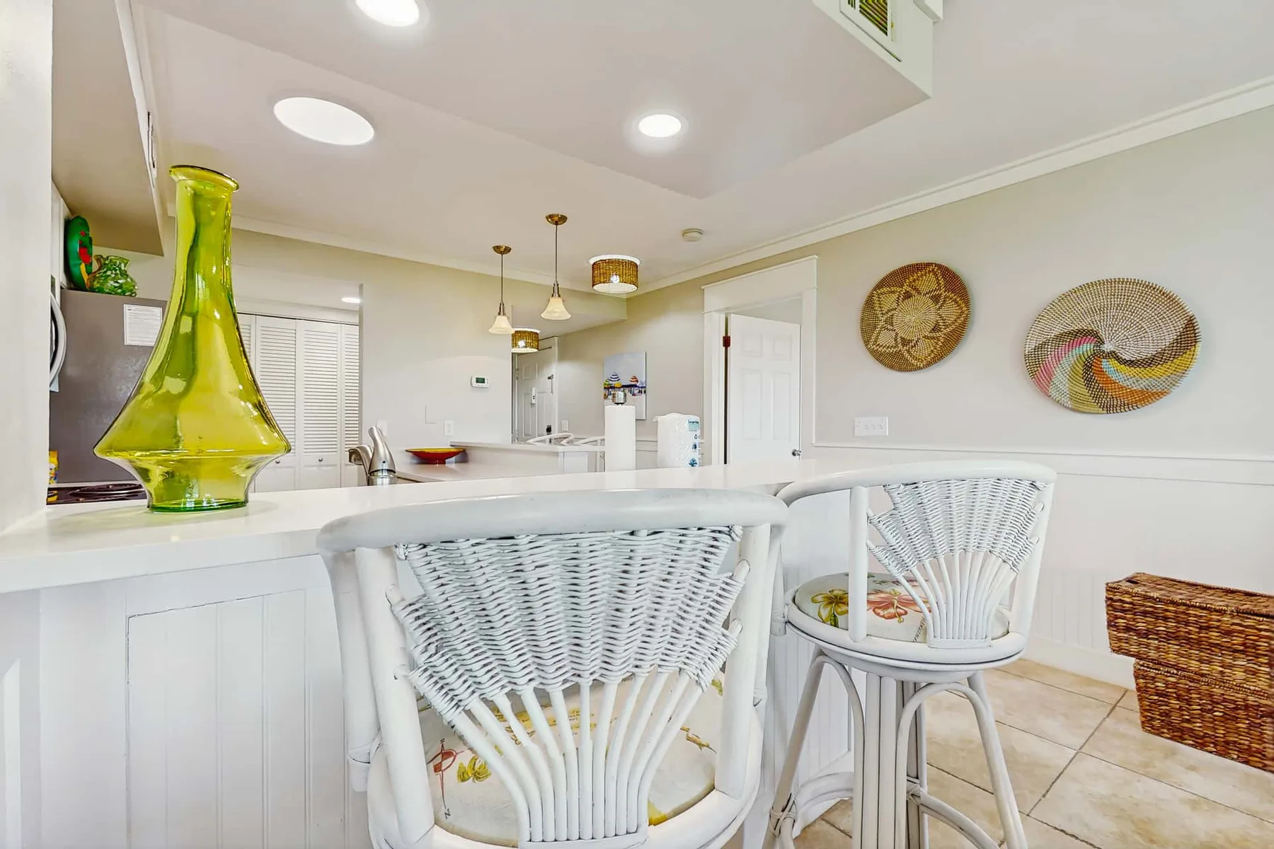 A bright kitchen and dining area with a white counter and woven seating.