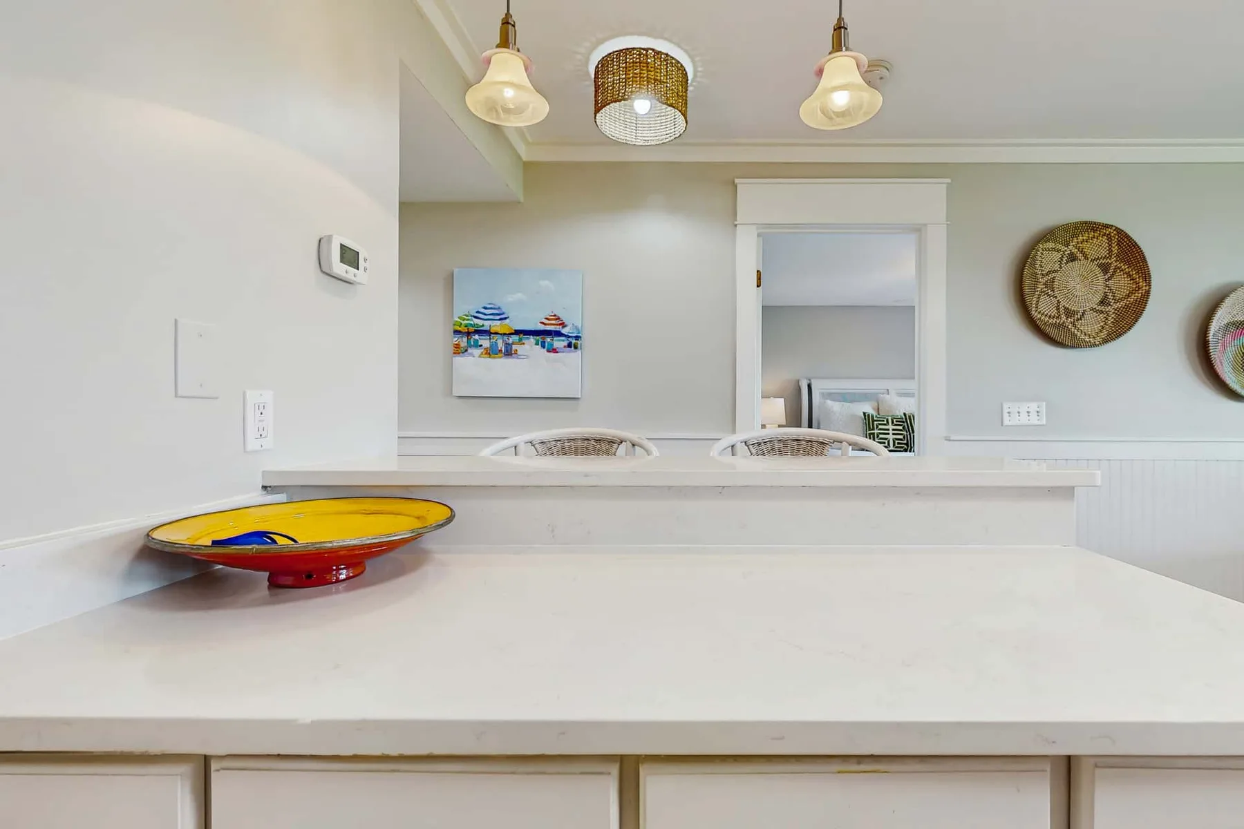 A bright kitchen counter with pendant lights and colorful wall art.