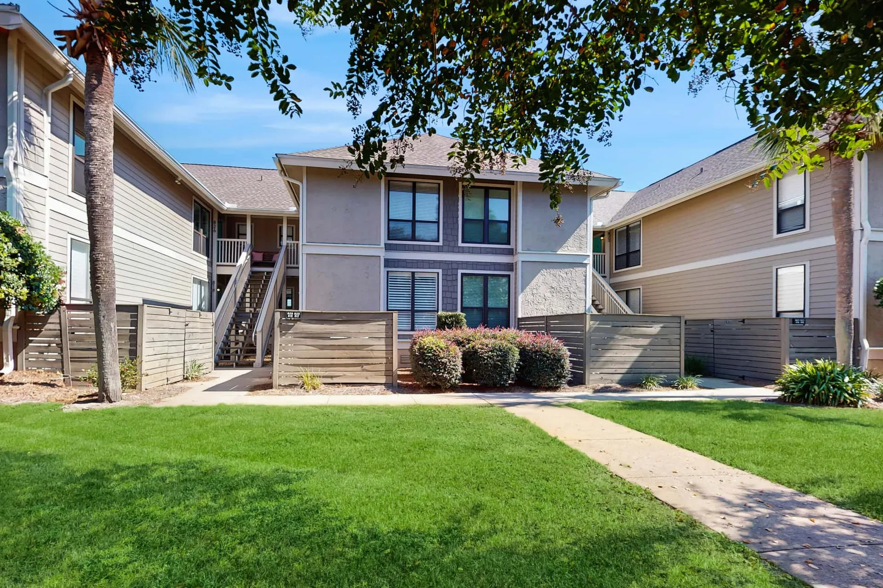 An apartment building with a green lawn and walkway in front.