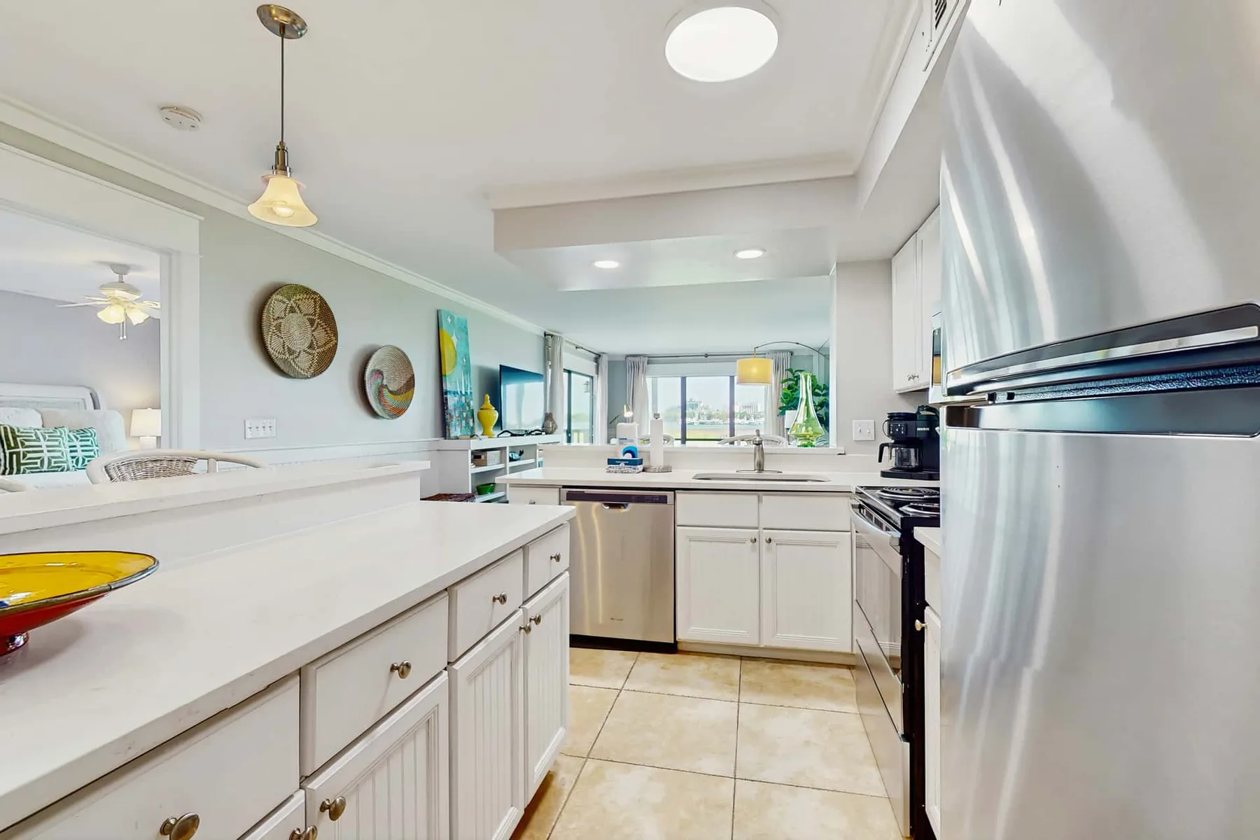A bright kitchen with white cabinetry, countertops, and stainless-steel appliances.