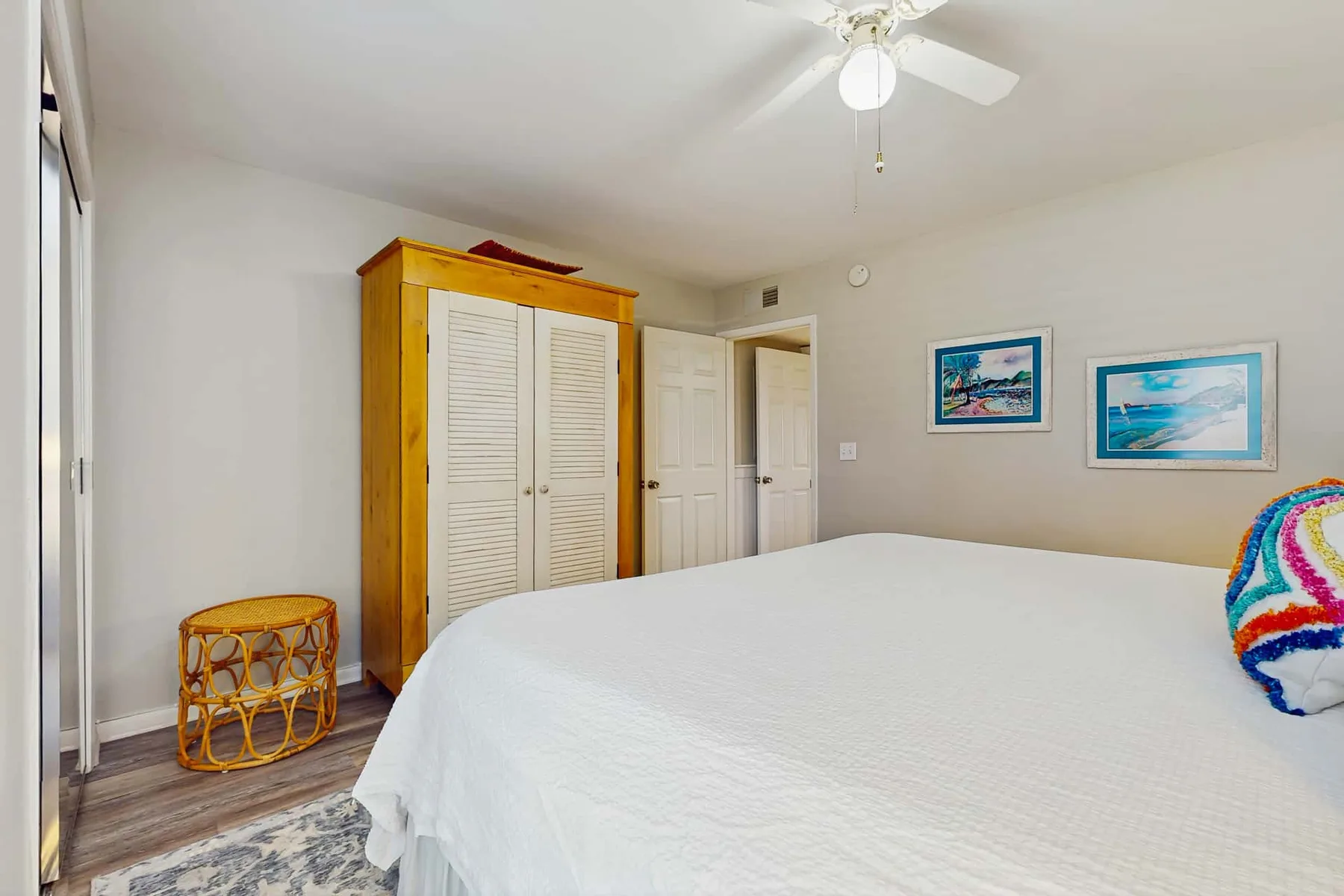 A bedroom with a large bed, a wooden wardrobe, and framed pictures on the wall.