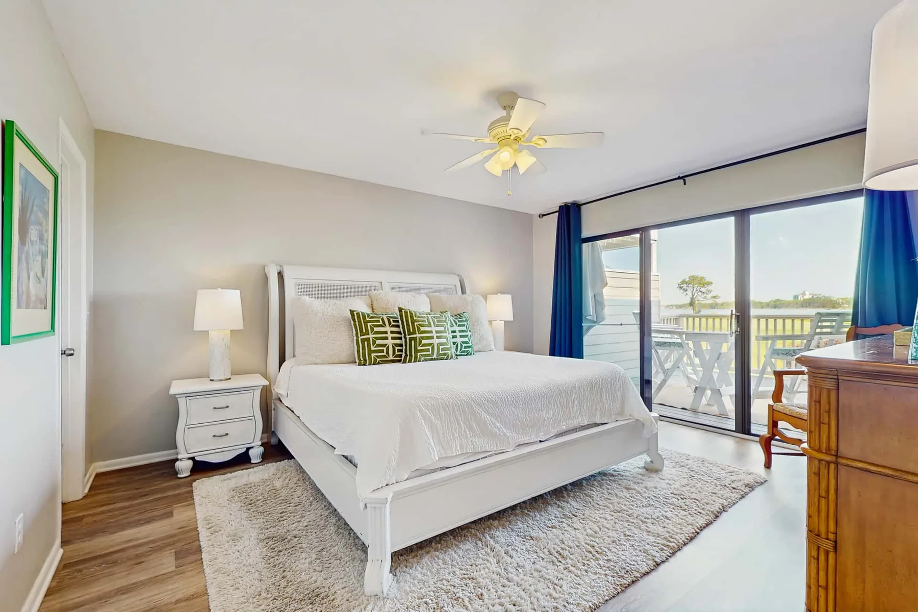 A bedroom with a large bed beside sliding glass doors opening onto a balcony.