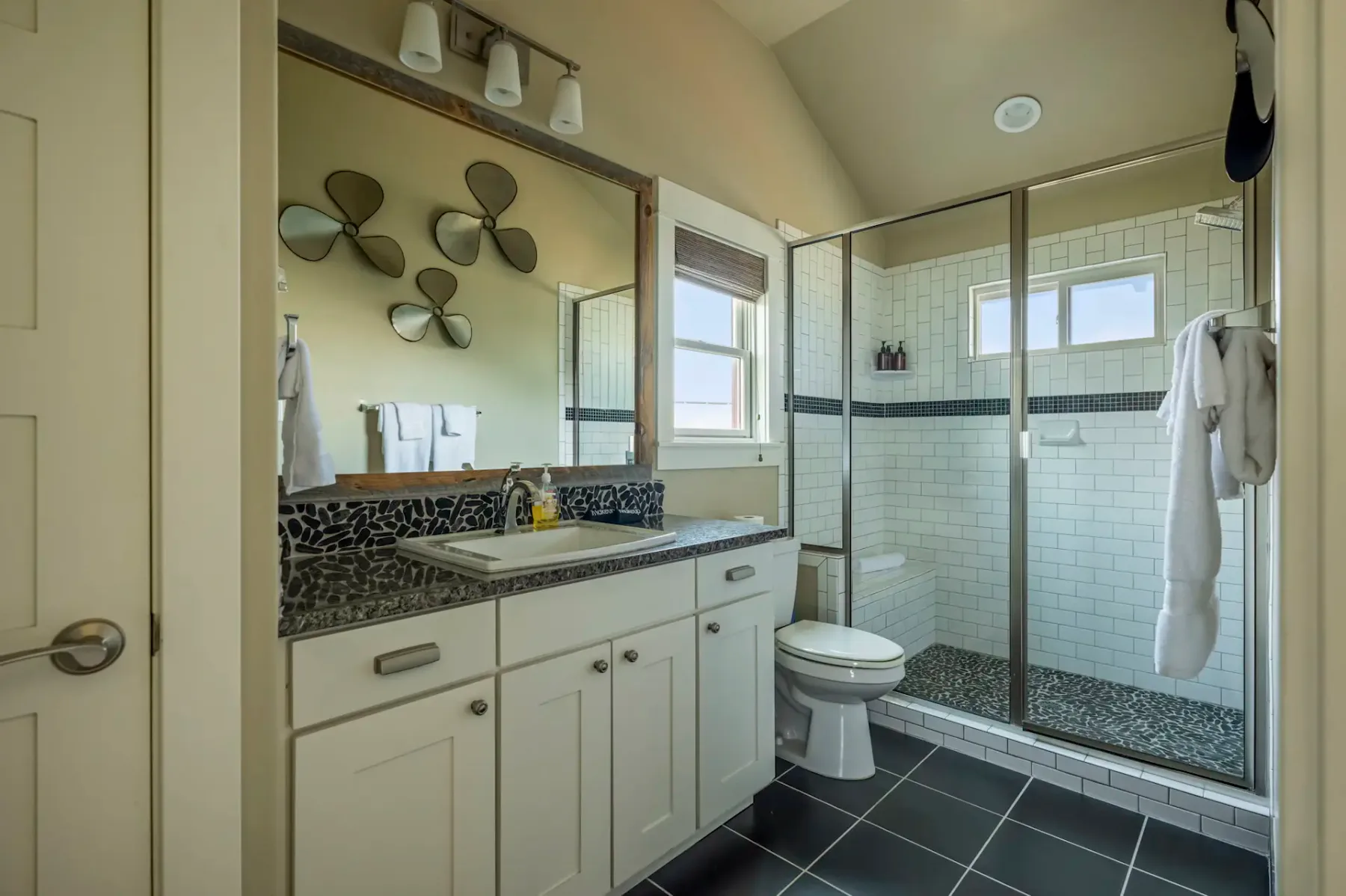 Bathroom with white cabinetry, a dark countertop, and a glass shower.