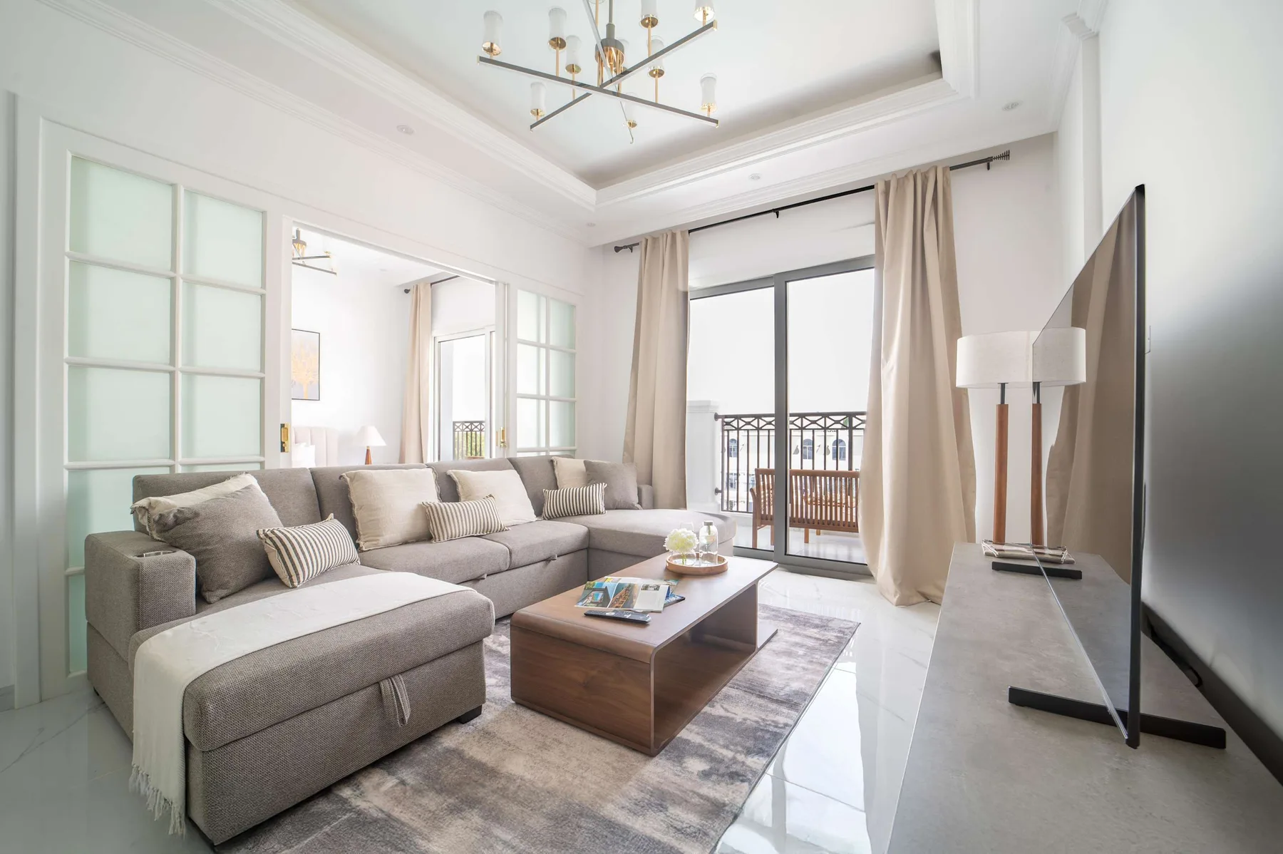 Sala de estar luminosa con sofá y puertas de vidrio hacia un balcón.