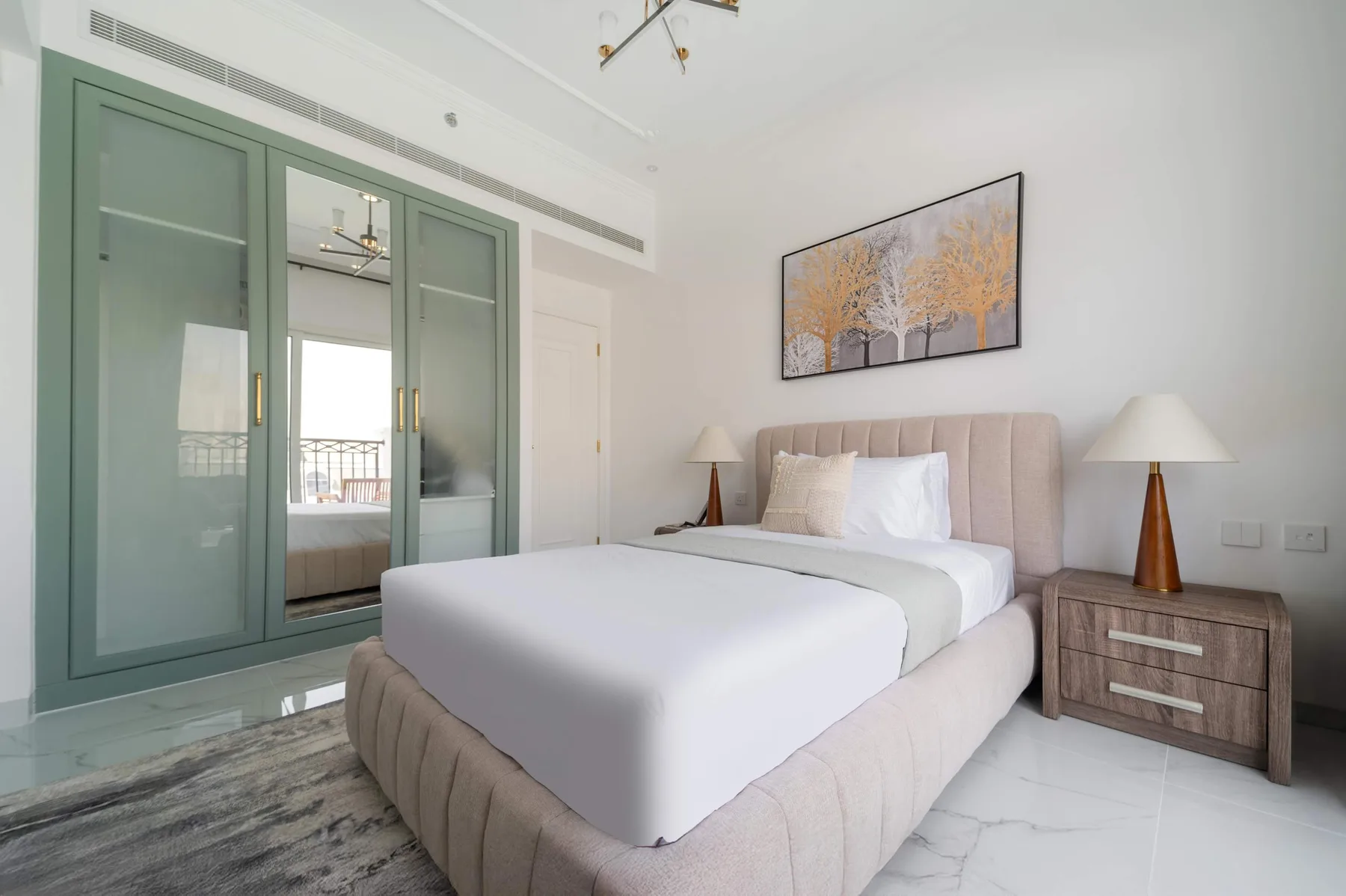 Un dormitorio luminoso con una cama tendida y un armario verde con espejos.