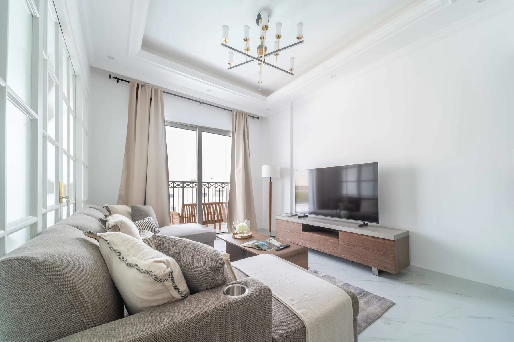 Una sala luminosa con asientos, un televisor y grandes ventanas.