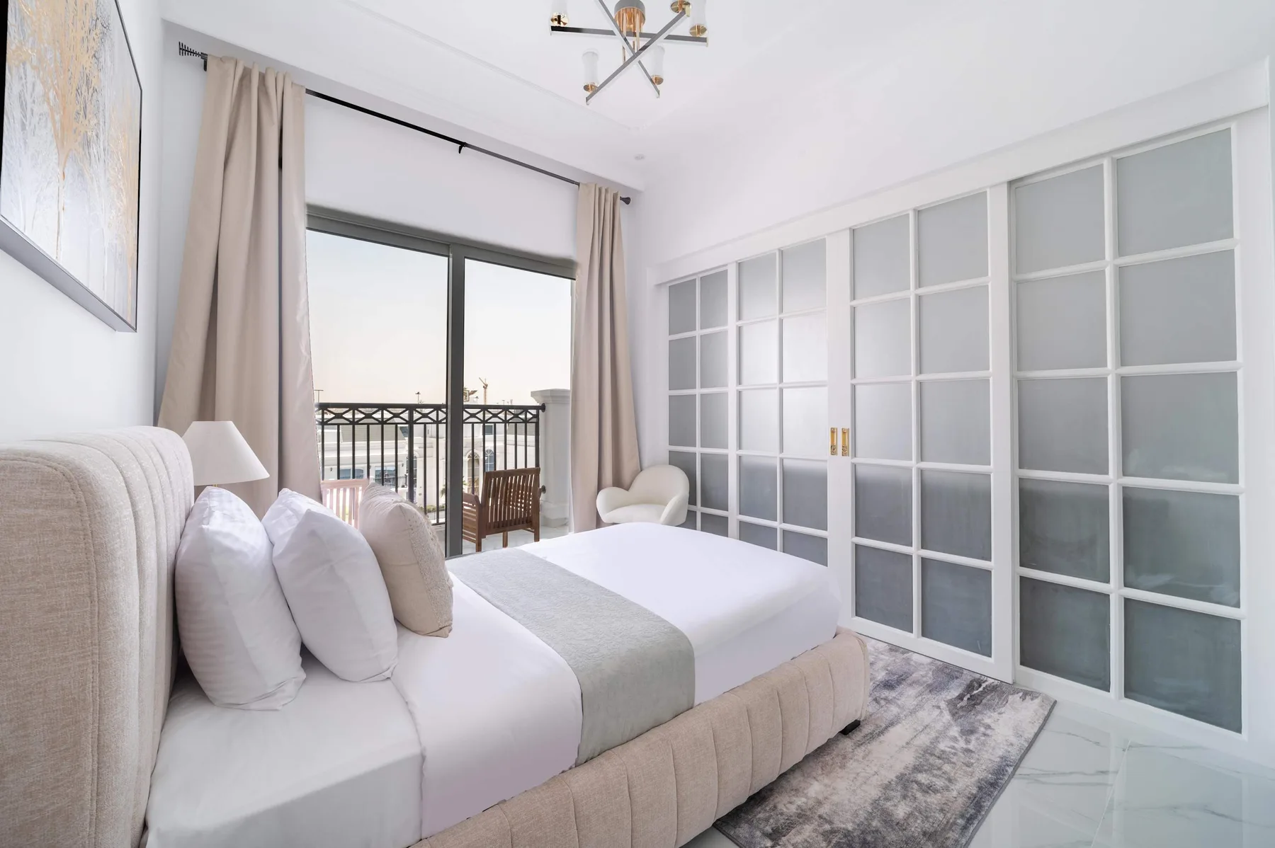Un dormitorio luminoso con una cama junto a puertas corredizas de vidrio y un balcón.