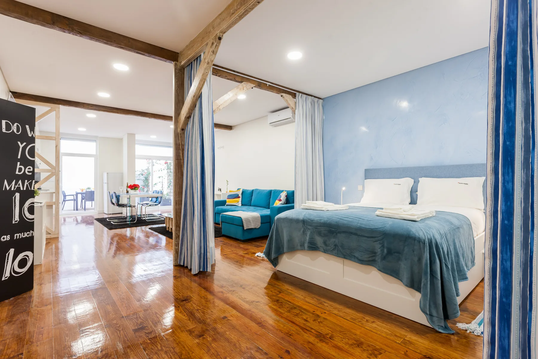 A bedroom with two beds and a blue seating area in the background.