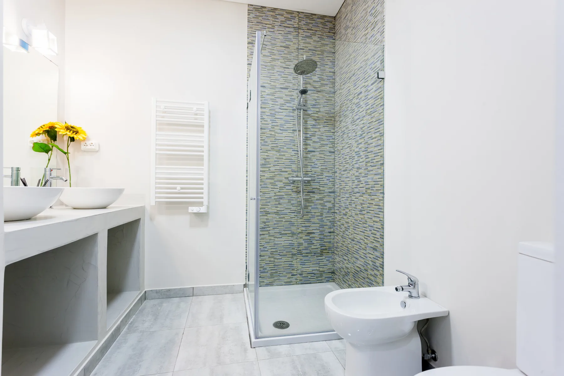Un baño luminoso con ducha alicatada, lavabo y bidé.