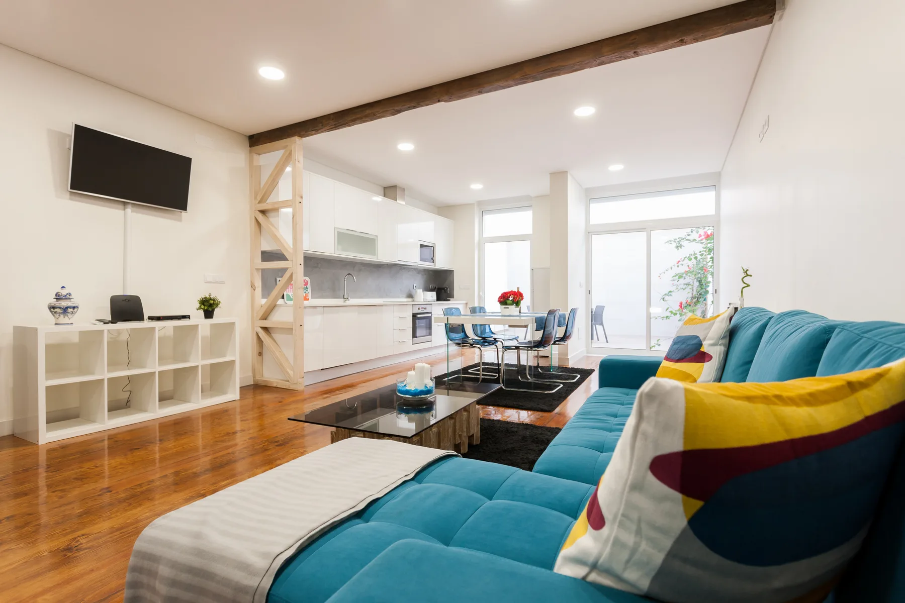Una luminosa sala de estar tipo estudio con asientos, mesa de comedor y cocina compacta.