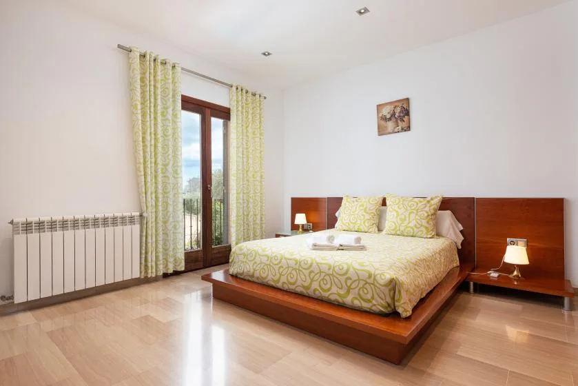 Un dormitorio con una cama doble, ropa de cama estampada y ventanas altas.