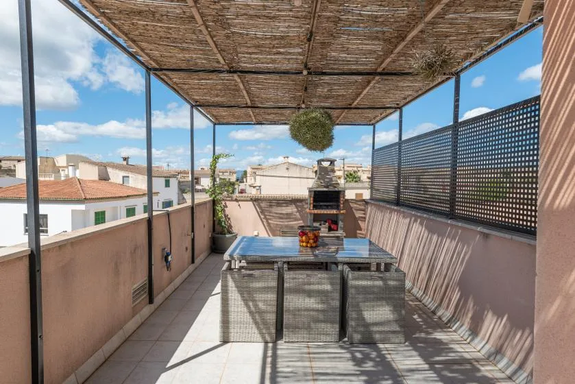 Una terraza en la azotea con una mesa de comedor bajo un toldo.