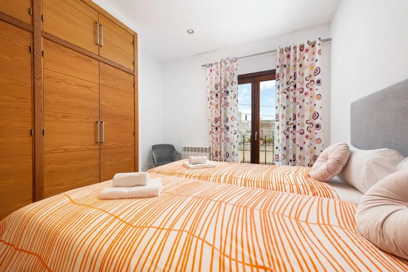 Un dormitorio con cama doble, armario de madera y cortinas estampadas.