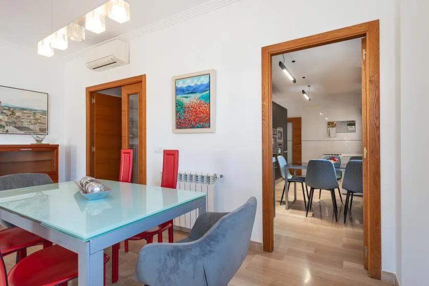 Comedor con una mesa de vidrio y una puerta abierta hacia otra habitación.