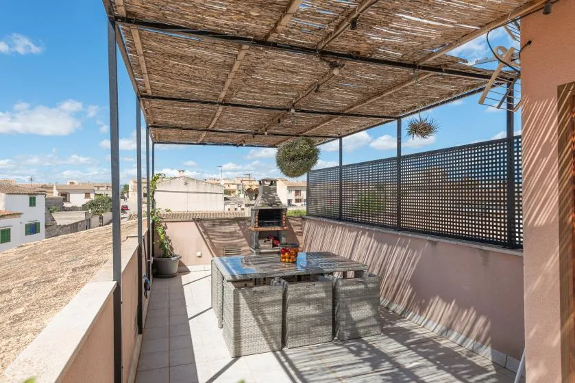 Una terraza en la azotea con una mesa de comedor bajo un toldo tejido.