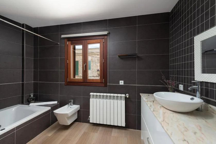 Un baño revestido de azulejos con bañera, lavabo suspendido y lavabo sobre la encimera.