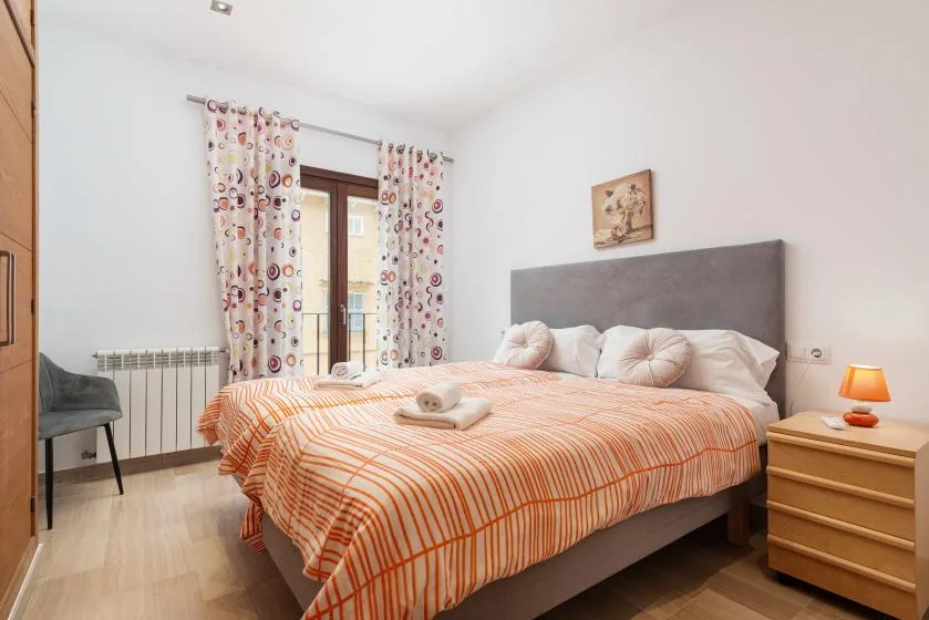 Un dormitorio con una cama grande vestida con ropa de cama a rayas naranjas y blancas.