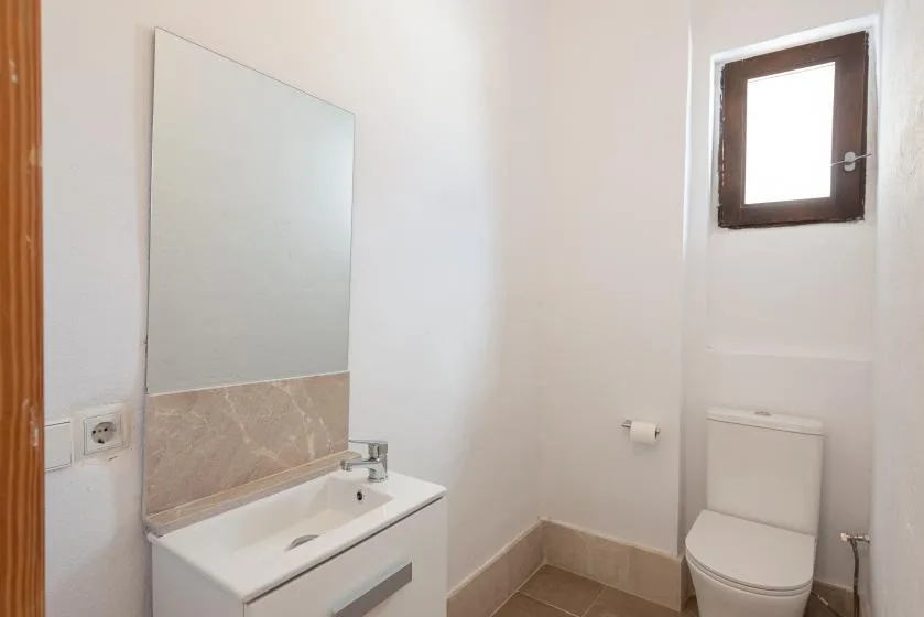 Un baño con lavabo, espejo e inodoro.