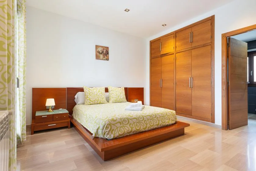 Un dormitorio con una cama de madera, ropa de cama estampada y armarios empotrados.