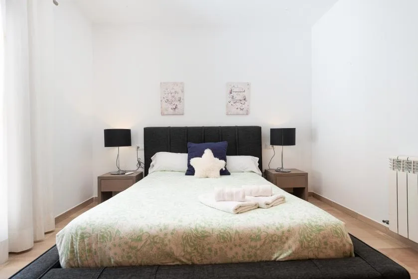 Un dormitorio con una cama doble, mesitas de noche y lámparas a juego.