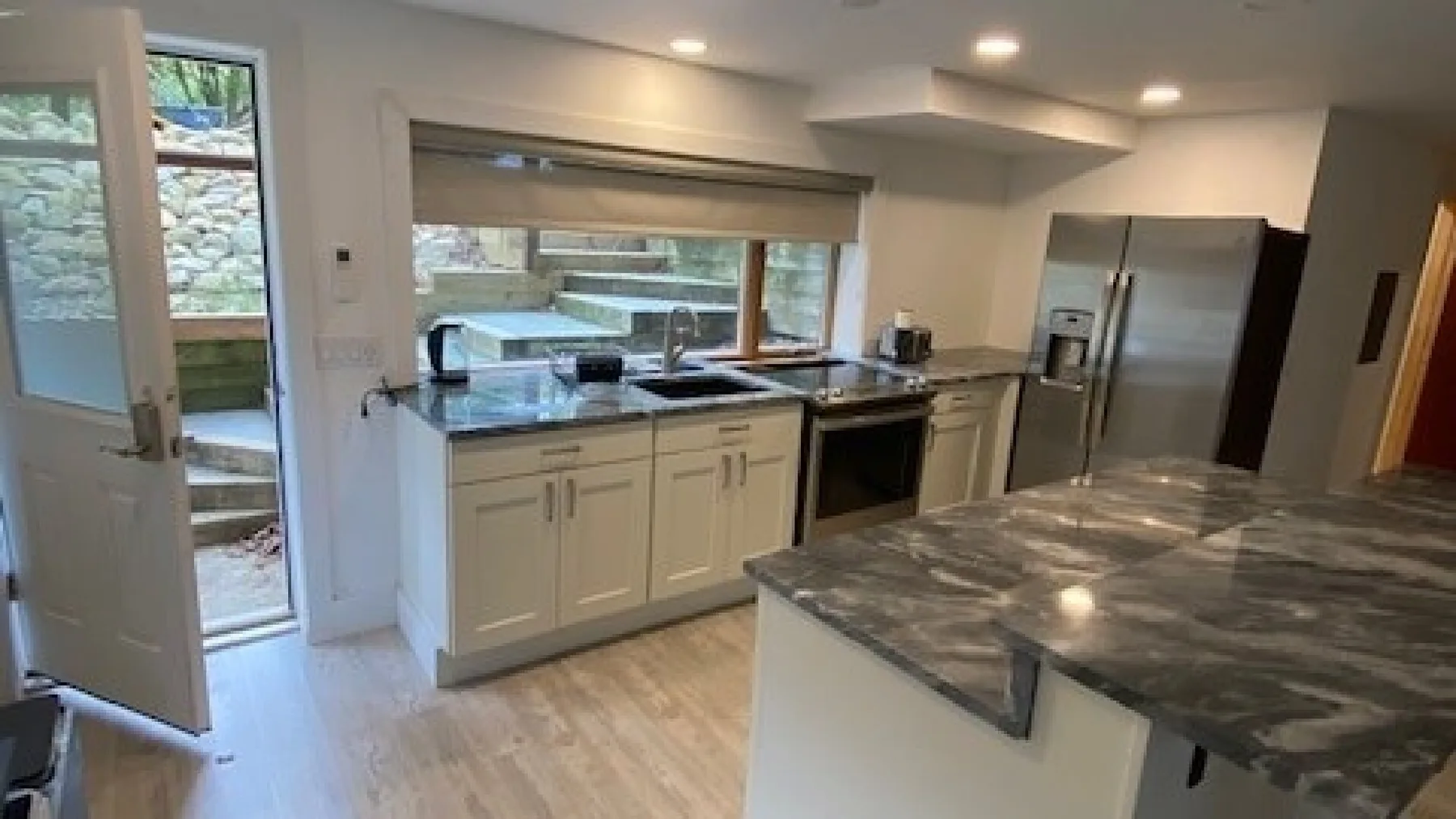 A modern kitchen with white cabinets, stainless steel appliances, and a large island.