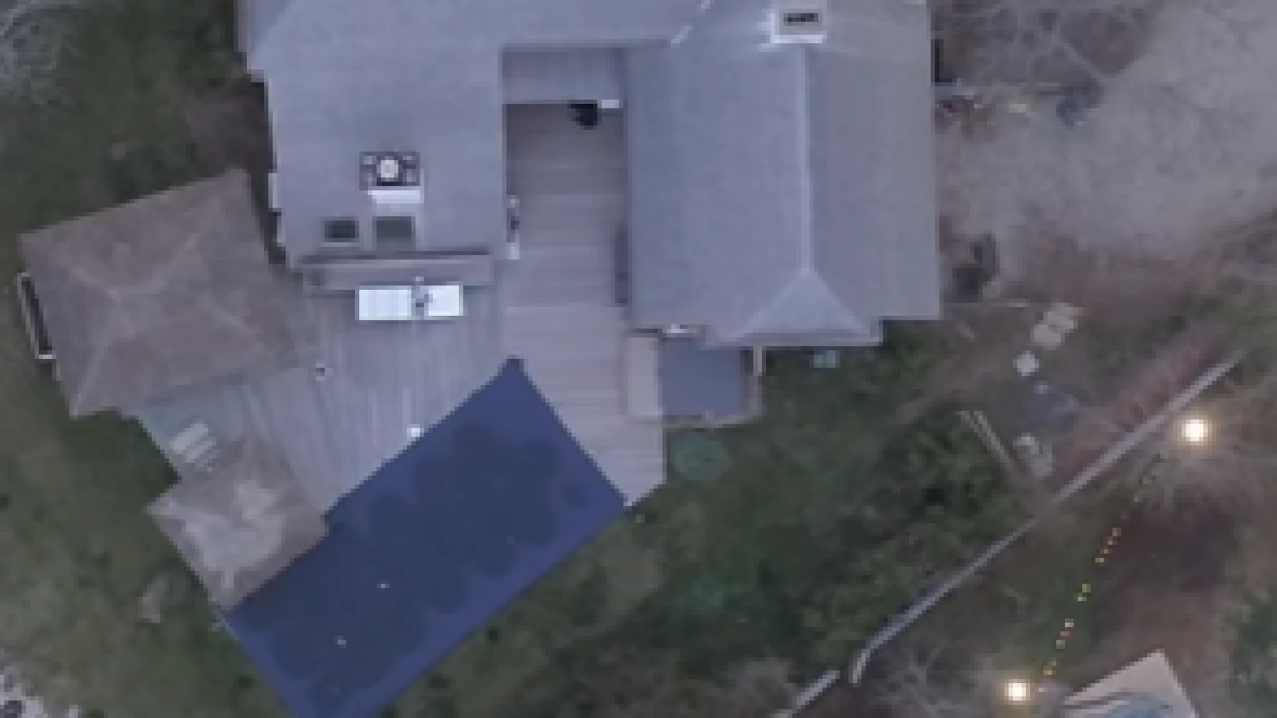 An aerial view of a house with a wooden deck and adjacent lawn.