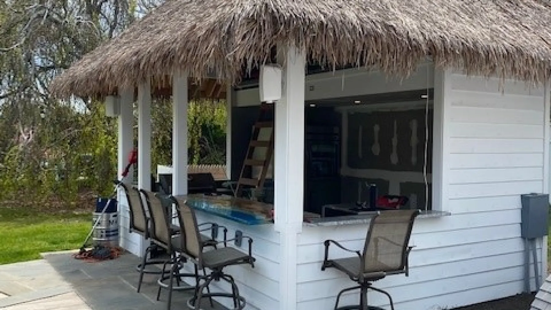 A thatched-roof outdoor bar opens onto a patio with seating.