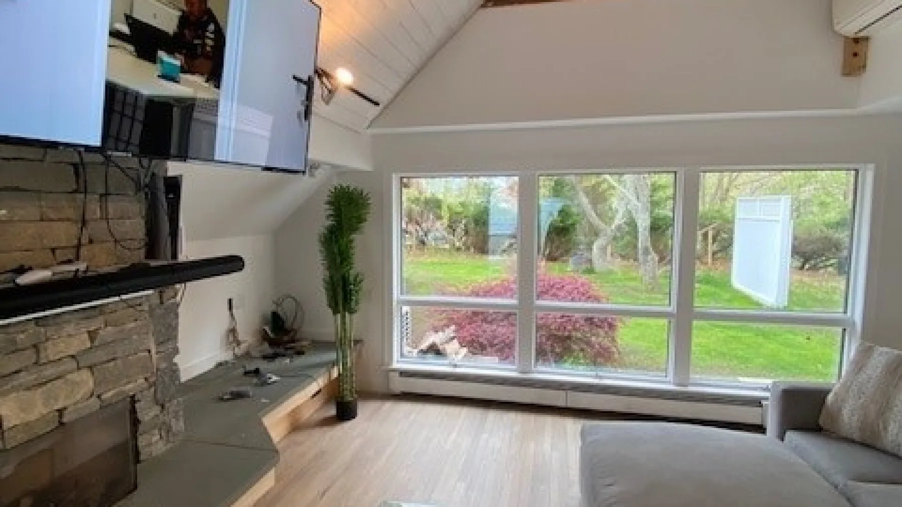A living room with a fireplace, seating, and large windows overlooking a garden.