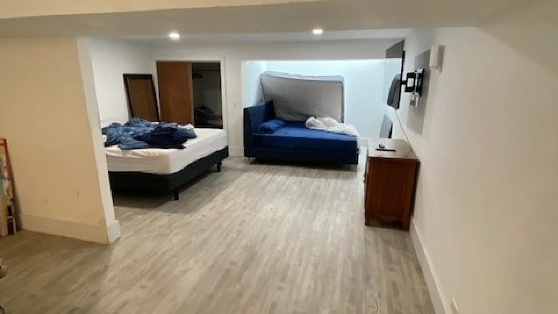 A bedroom with two beds and a wooden dresser.