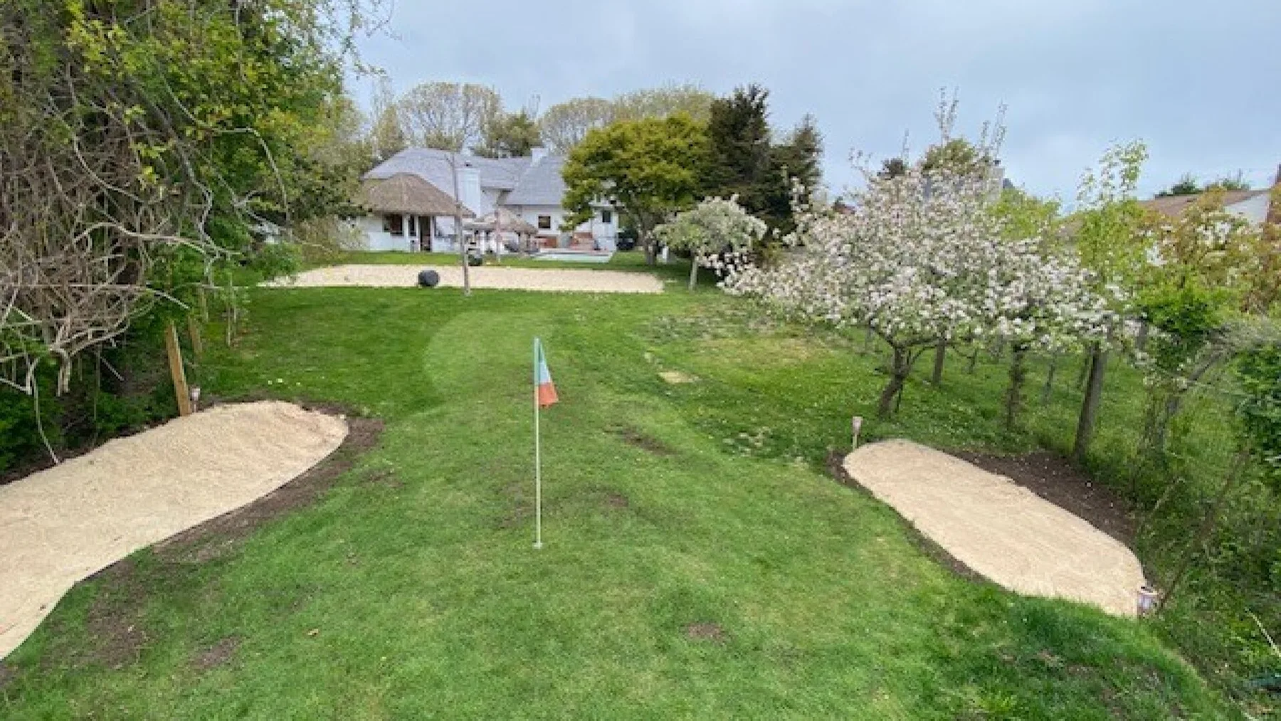 A grassy garden with two sand bunkers and a small flag.