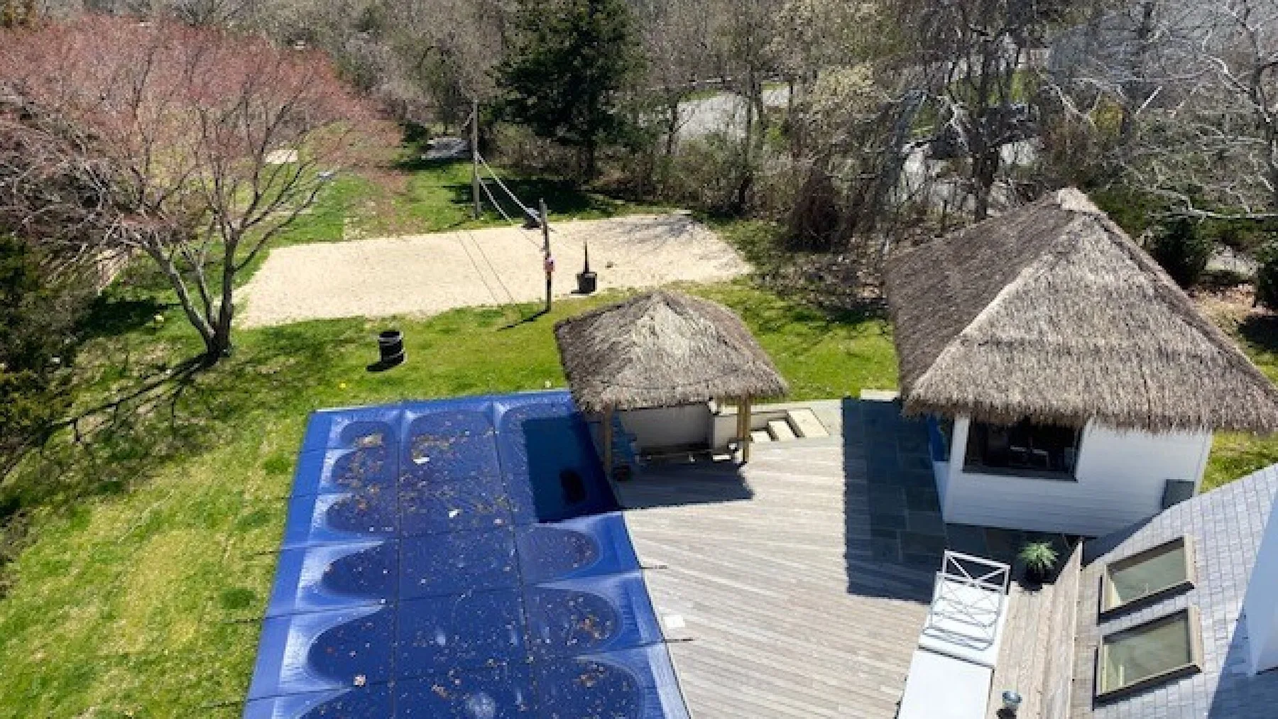 An elevated view shows a deck with thatched-roof structures beside blue solar panels.