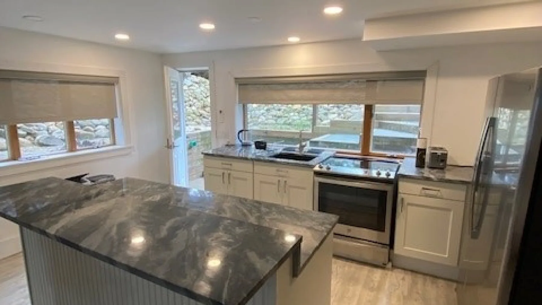A bright kitchen with a large island, cabinetry, and windows overlooking the outdoors.