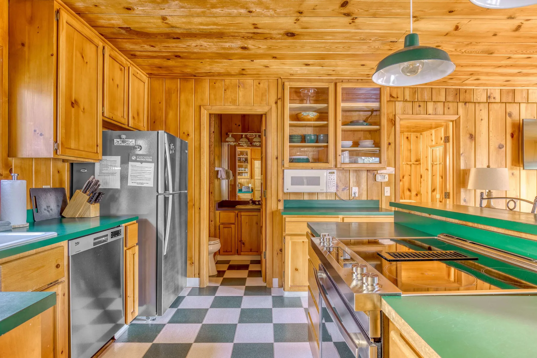 A wood-paneled kitchen with green countertops and a checkered floor.