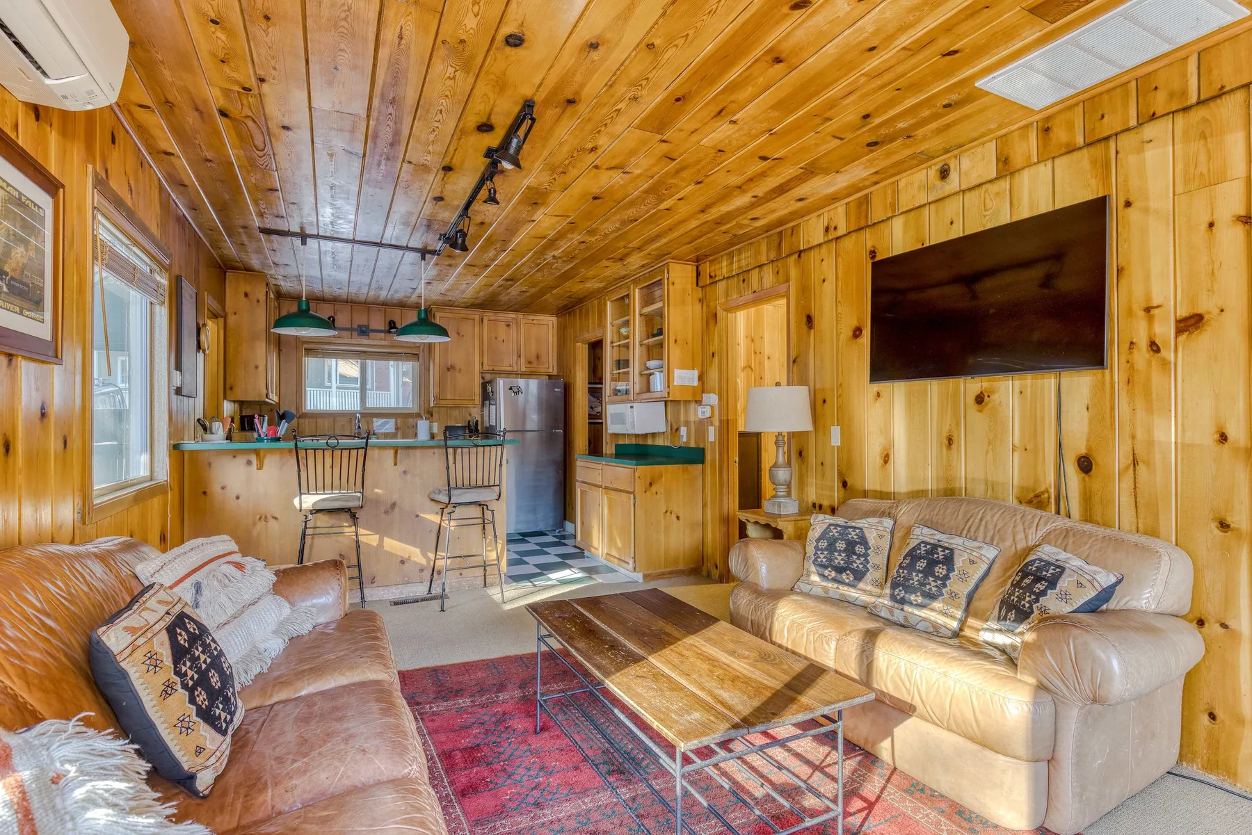A wood-paneled living room with seating, a coffee table, and a television.