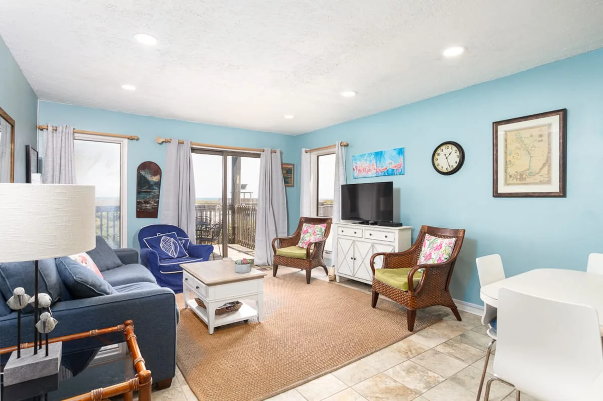A bright living room with blue seating, a coffee table, and a television.