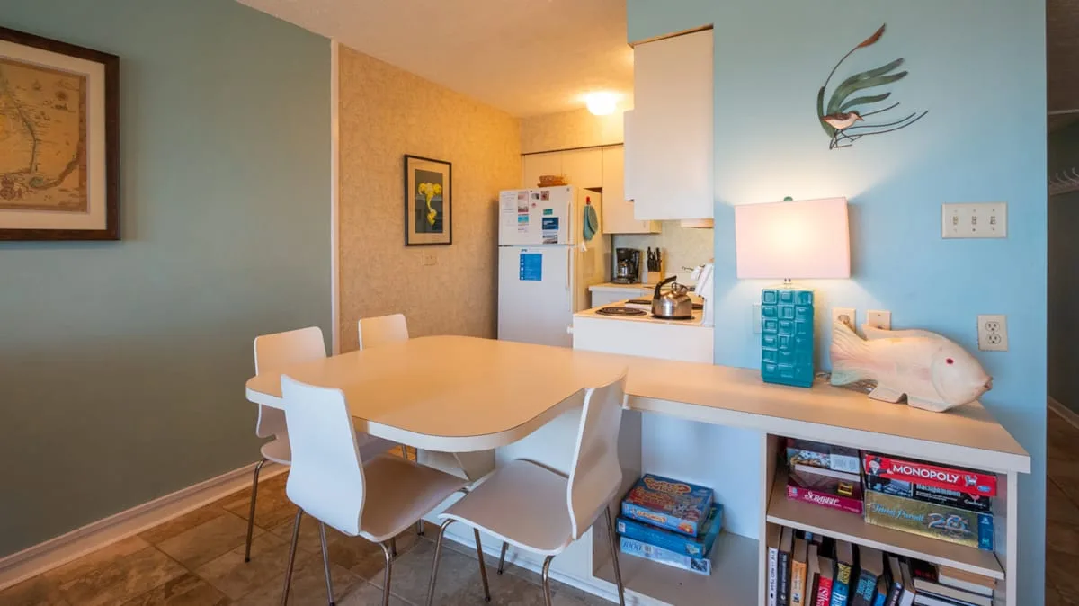 A dining area beside a kitchen counter, with white seating and blue walls.