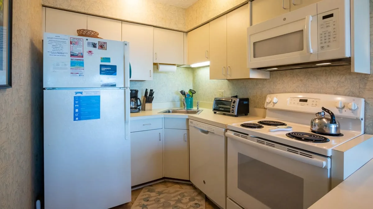 A compact kitchen with light cabinets, a refrigerator, and a stove.