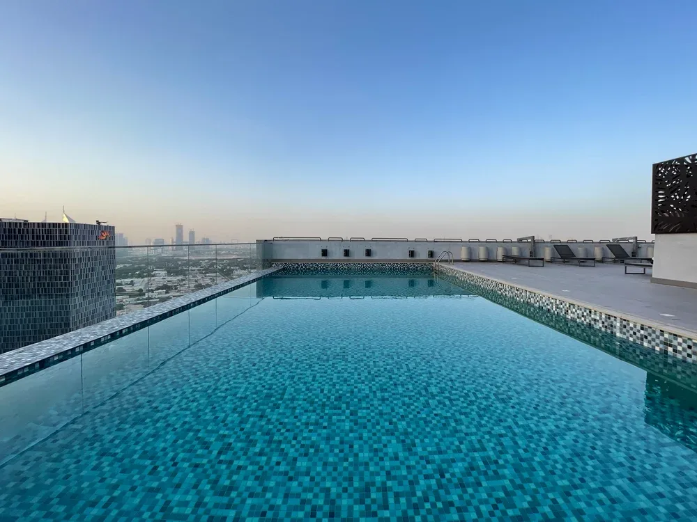 Rooftop swimming pool with a city skyline visible in the distance.